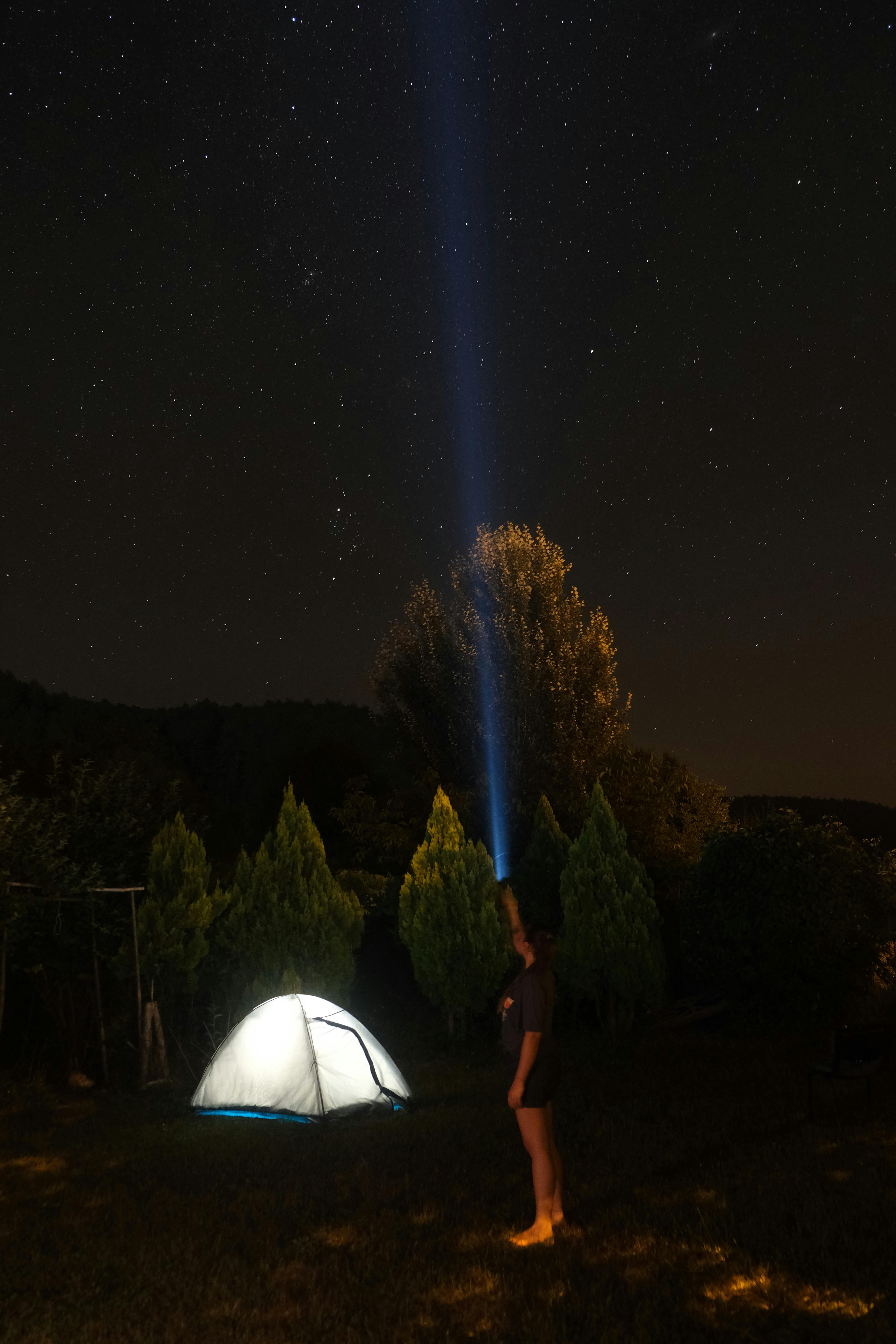 Woman shining a flashlight beside a tent
