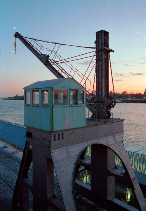 Free Rustic crane by the harbor against a vibrant sunset backdrop. Stock Photo