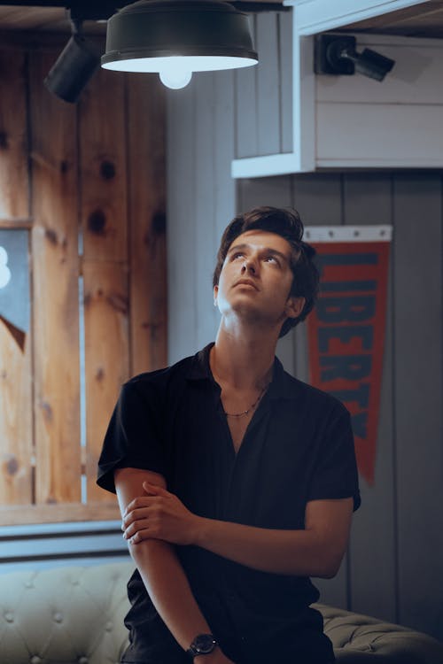 Man in Black Shirt Looking at Lamp