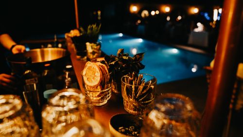 Free A stylish poolside bar setup at night featuring fresh garnishes and warm ambient lighting. Stock Photo