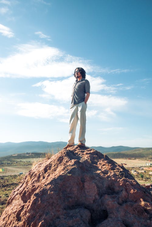Free Man Standing on Rock against Blue Sky Stock Photo