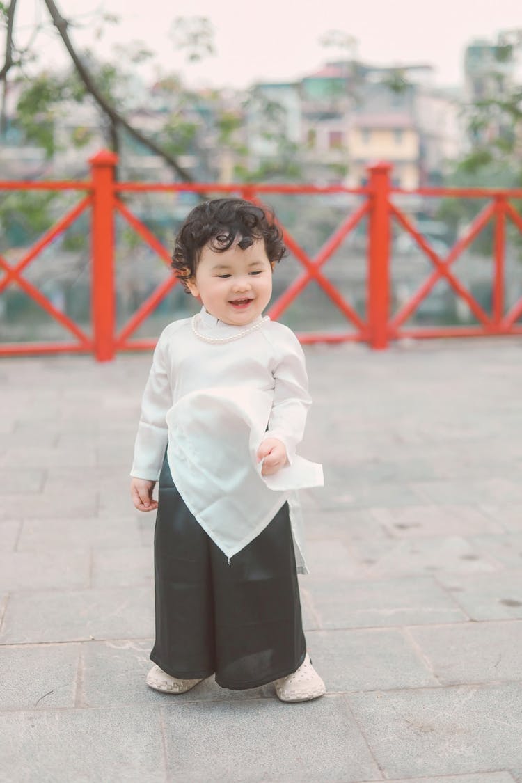 Little Boy In Changpao Standing On Bridge