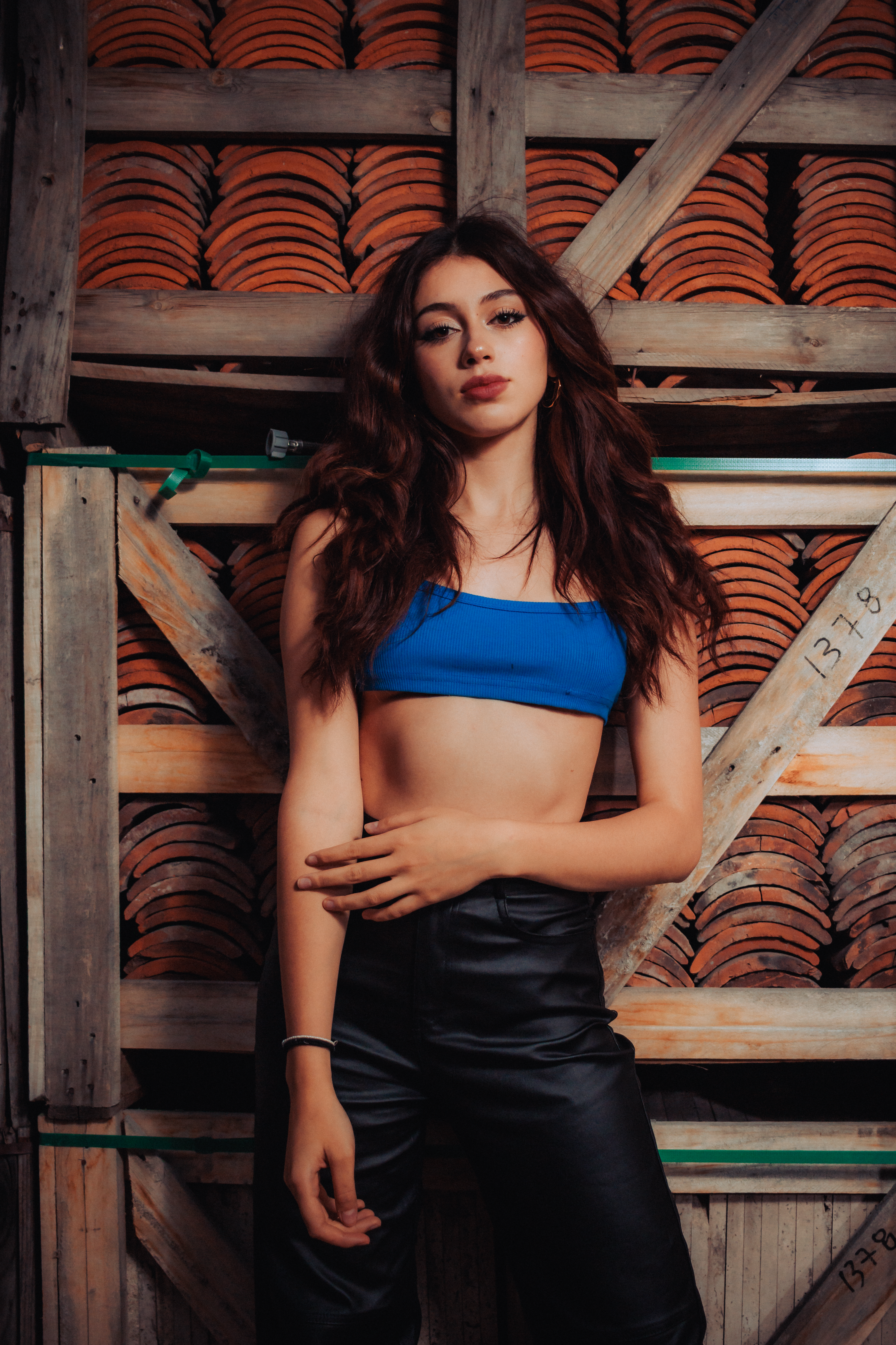 Stylish young woman posing in trendy outfit against a rustic wooden background.