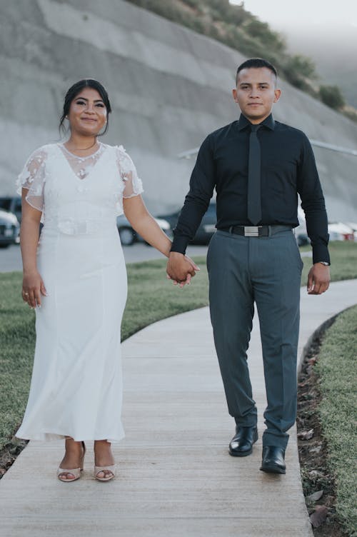 Smiling Newlyweds Standing and Holding Hands