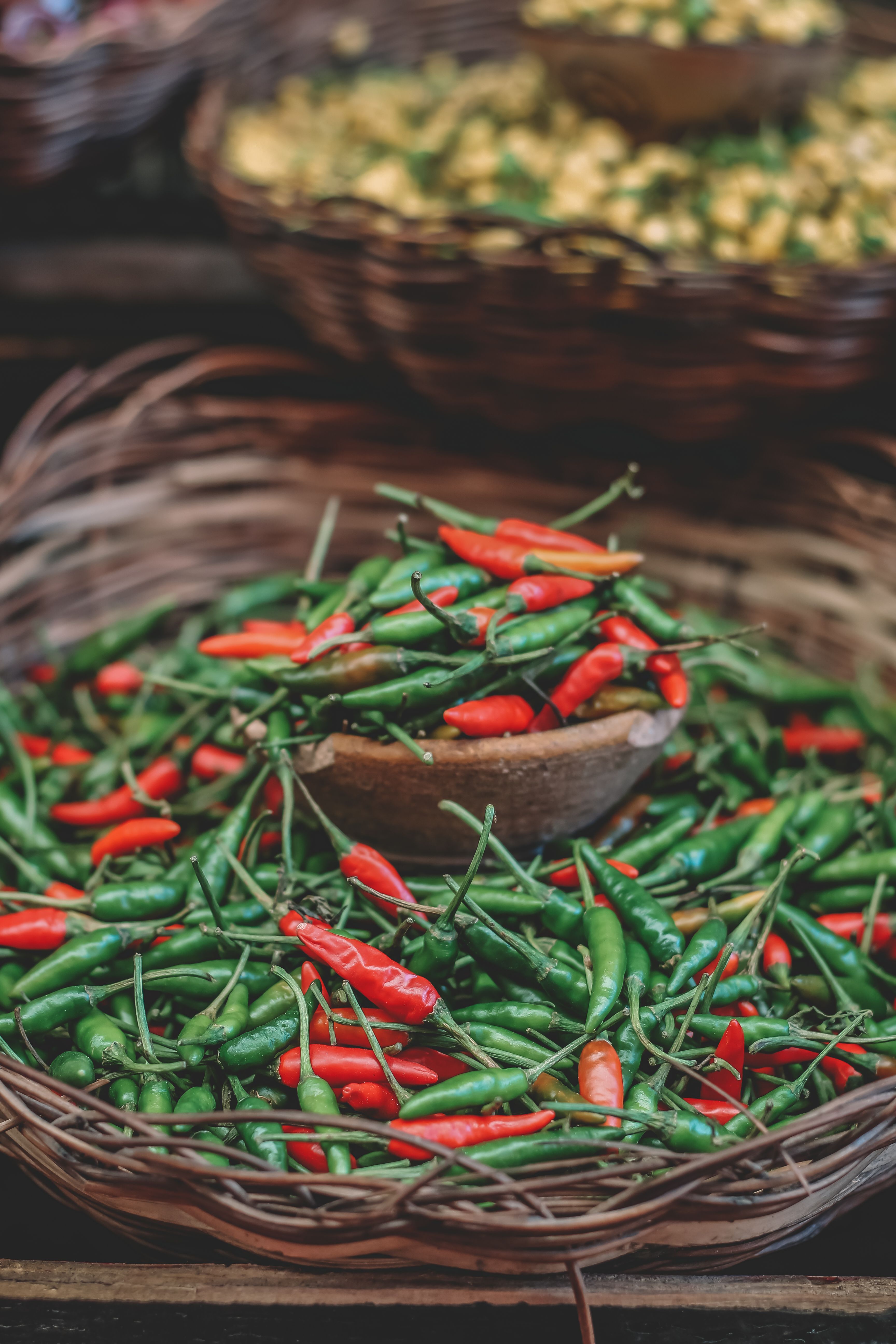 Fotomural Pimientos chili rojos y verdes frescos exhibidos en cestas tejidas en un puesto de mercado.