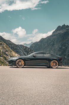 Sleek black sports car parked in scenic mountain setting, showcasing elegance and natural beauty.