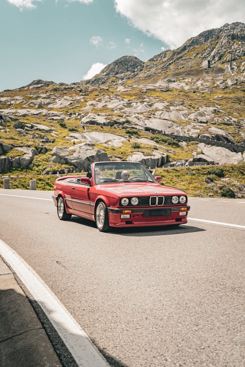 A Red Convertible BMW E30 on a Road in Rocky Mountains 