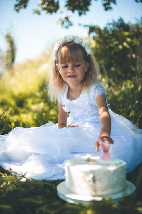 Blonde Girl in White Dress Sitting with Cake