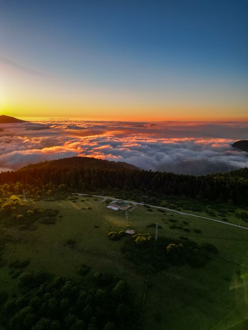Free Stunning aerial view capturing sunset over a mountainous landscape with vibrant clouds. Stock Photo