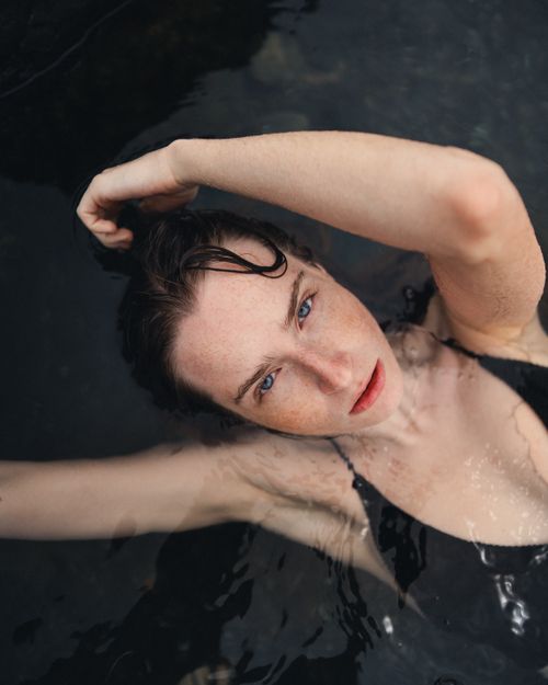 Free A serene portrait of a woman relaxing and posing gracefully in calm water, offering a tranquil vibe. Stock Photo