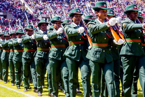 Women in Official Army Uniforms Marching on a Football Stadium 