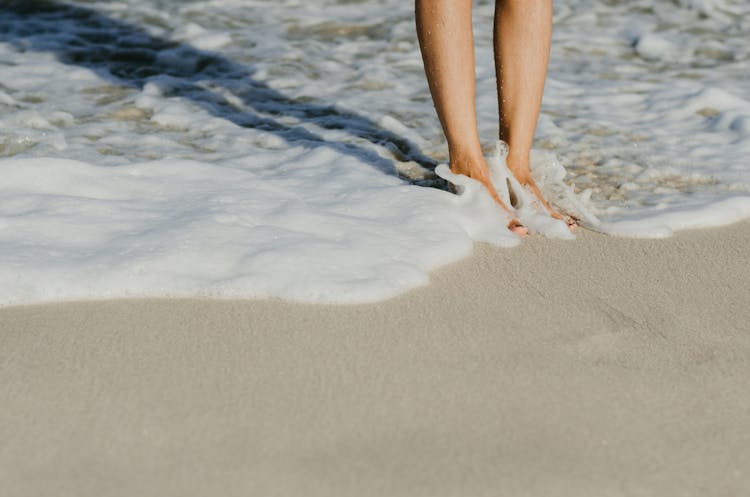 Person Standing On Beach In Sea Wave