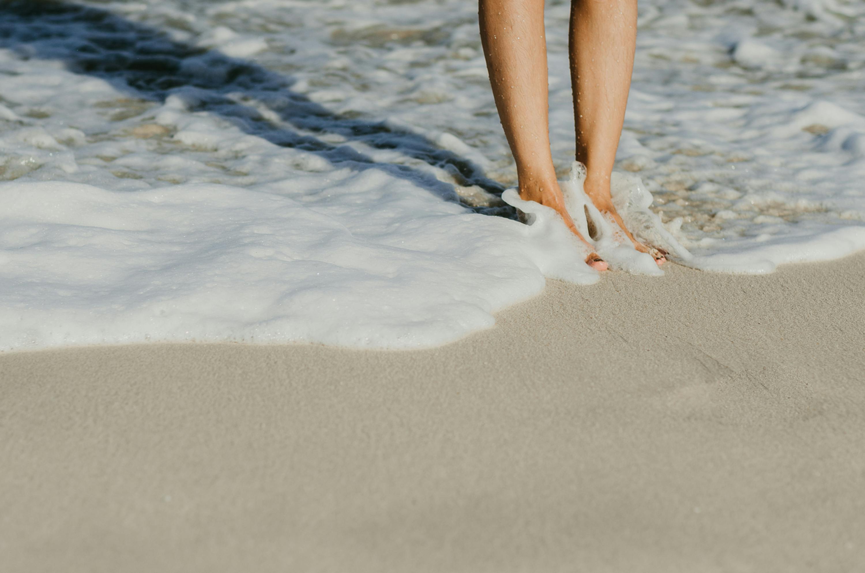 Person Standing on Beach in Sea Wave · Free Stock Photo