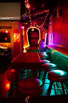 Vibrant neon-lit bar with artistic decor and empty seating, creating an inviting and modern atmosphere.