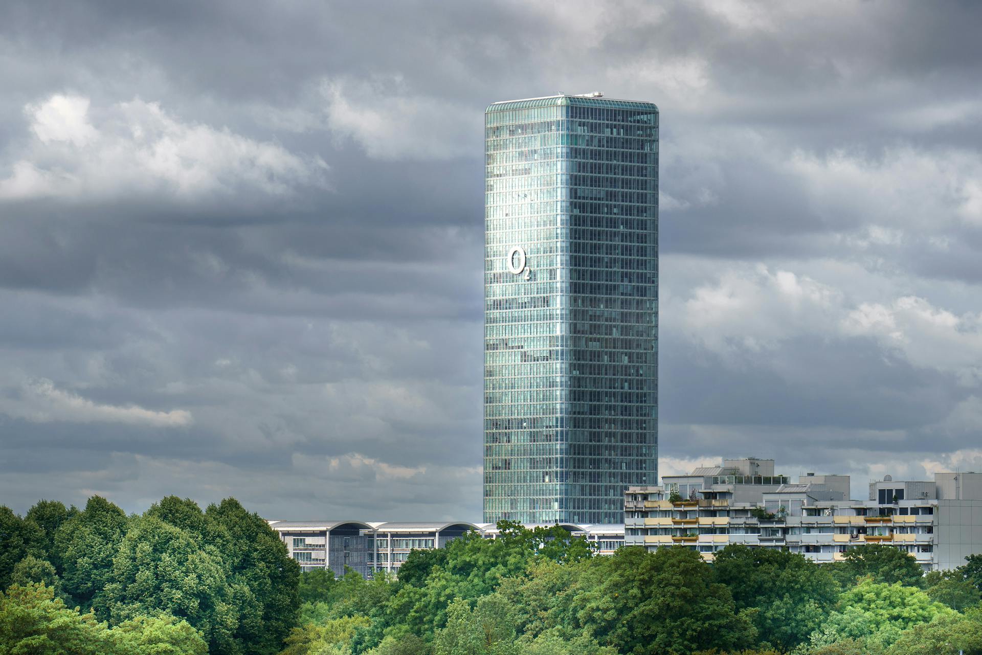 The Highlight Tower in Munich rises against a backdrop of dramatic clouds, capturing urban architecture.