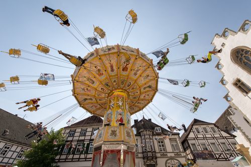 Free Colorful carousel ride spins against Brakel's historic old town backdrop, capturing lively entertainment. Stock Photo