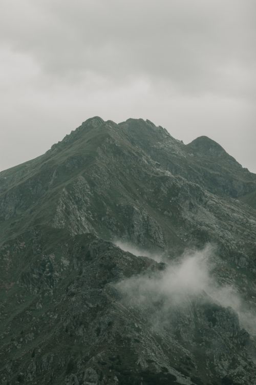 Free A moody mountain peak surrounded by clouds, showcasing rugged rocky terrain and a dramatic atmosphere. Stock Photo
