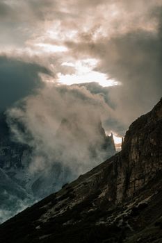 Atmospheric sunrise over the cloud-covered Dolomite peaks in Cortina d'Ampezzo, Italy.