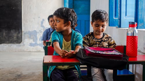 Two children sitting at desks in a classroom