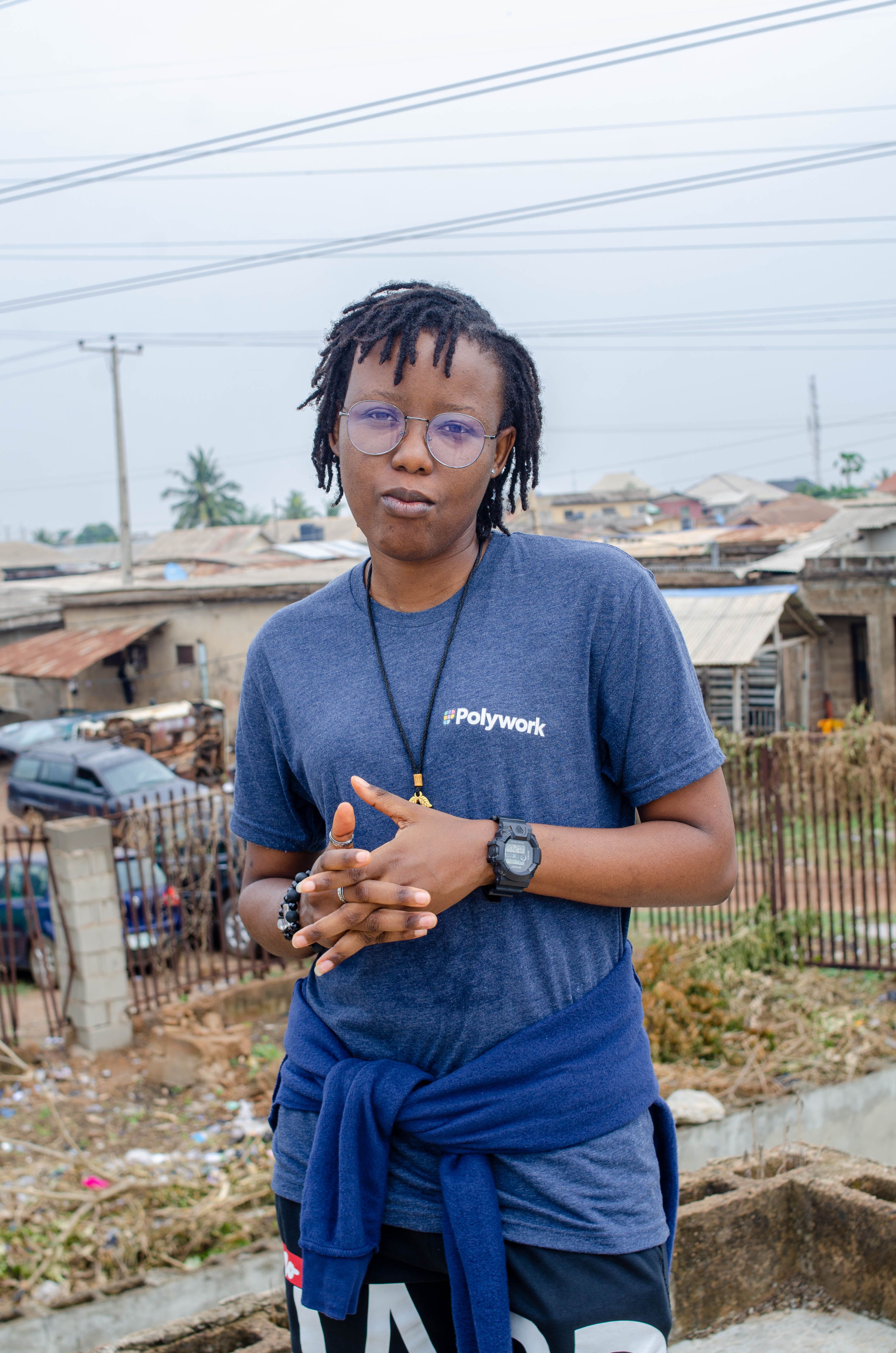 Woman with braids and eyeglasses standing outdoors in an urban area.