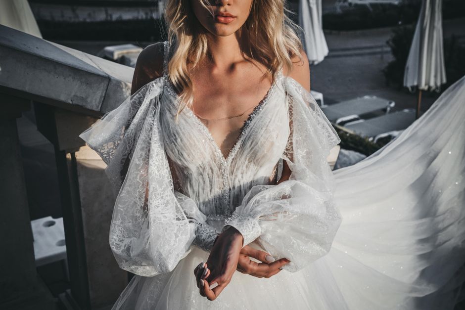 A beautiful bride in an elegant lace wedding dress standing outdoors, exuding grace and style.