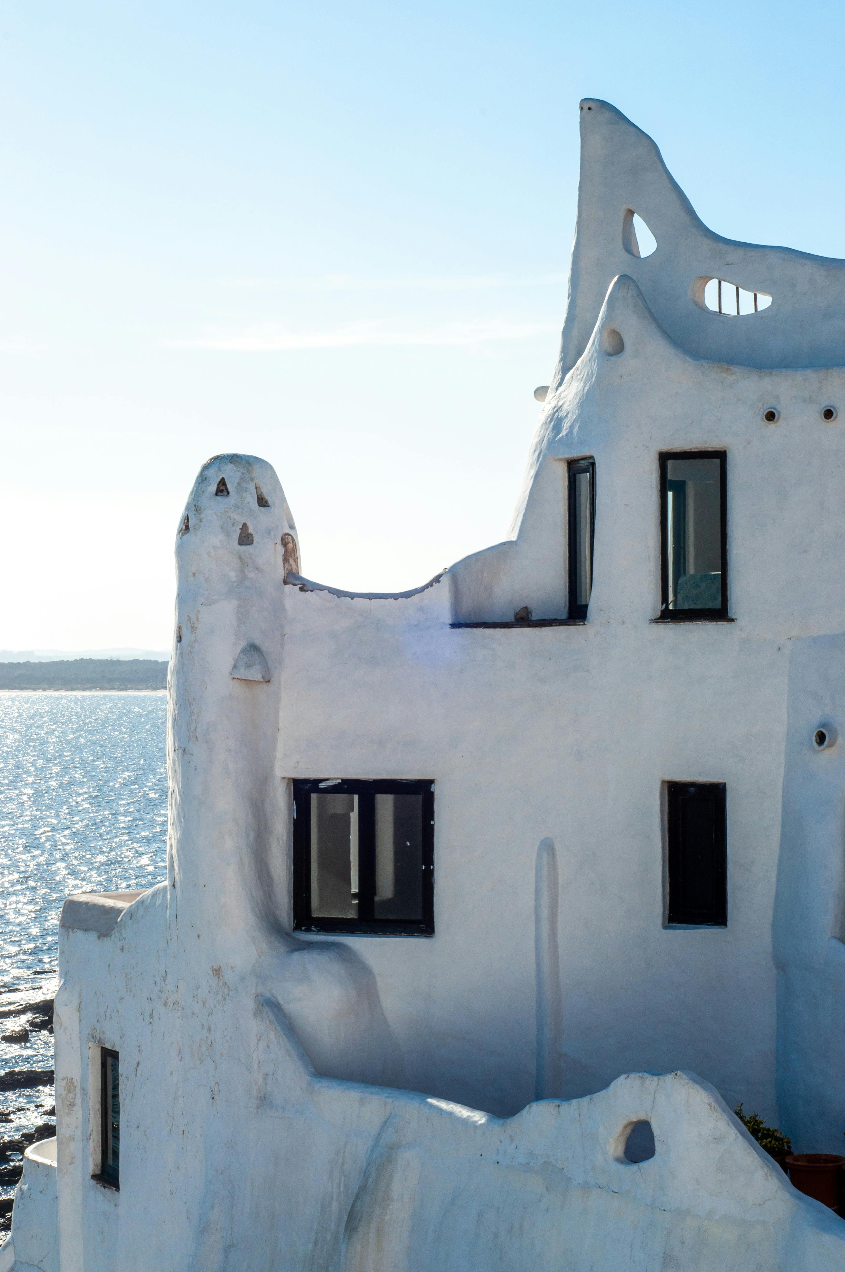 Beautiful white stucco building overlooking the sea with unique architectural details.