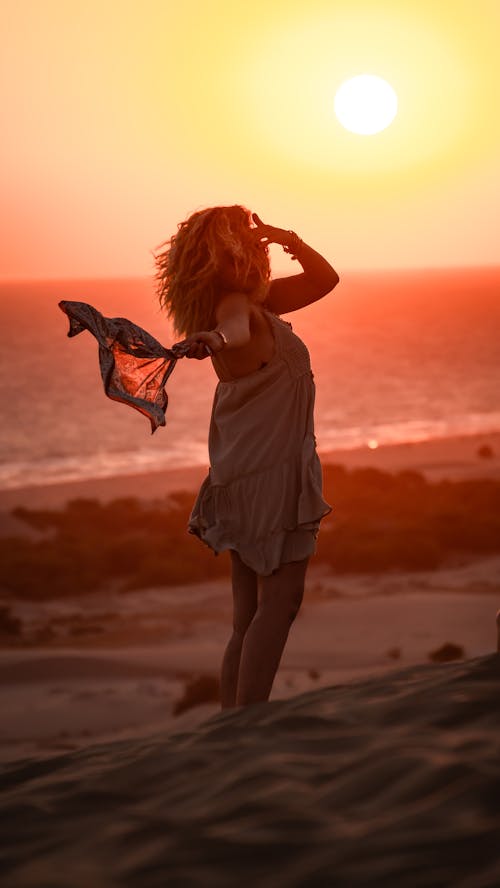 Standing Woman Holding Scarf in Hand at Sunset