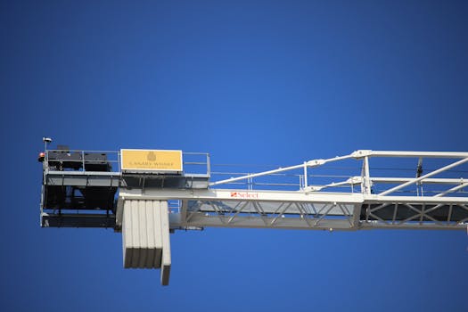 A construction crane at Canary Wharf extends against a clear blue sky, symbolizing urban development.