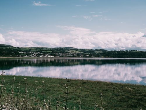 Free Serene landscape of a calm lake reflecting clouds in Conwy, Wales. Stock Photo