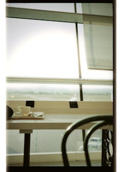Empty airport table with coffee cup and tray by a large window with a view.