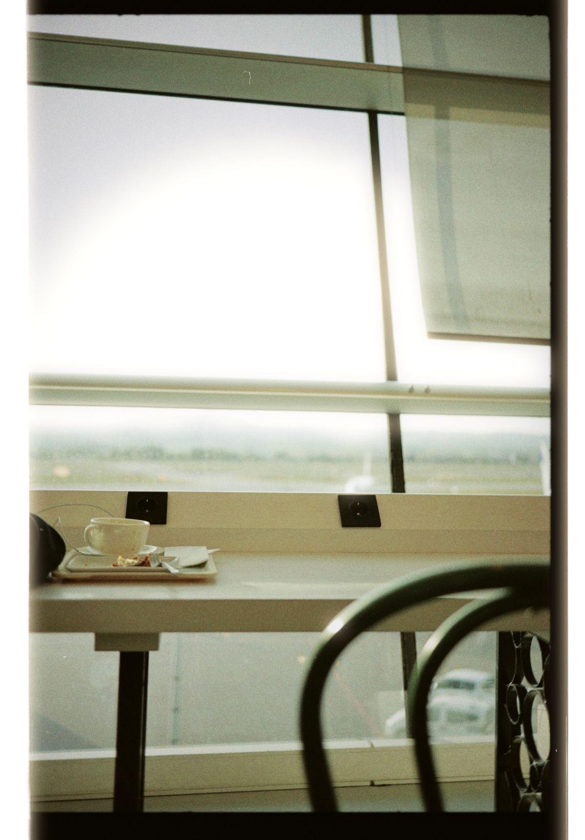 A coffee cup and tray on a terminal table beside a window overlooking the runway