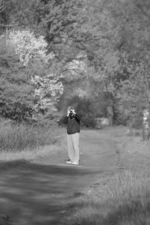 Man Taking Pictures on Dirt Road in Black and White