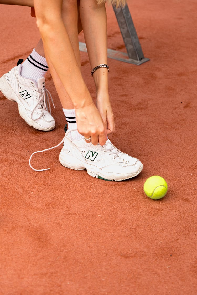 Person Tying Shoes On Tennis Court