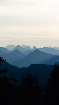 Scenic aerial view of the Tyrolean mountain range silhouetted against a dawn sky, capturing layers of peaks and soft light.