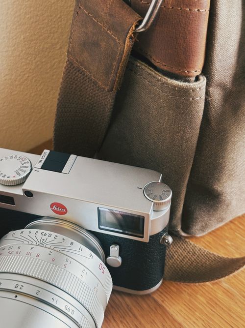 Free A detailed shot of a vintage camera with a stylish leather bag on a wooden surface. Stock Photo