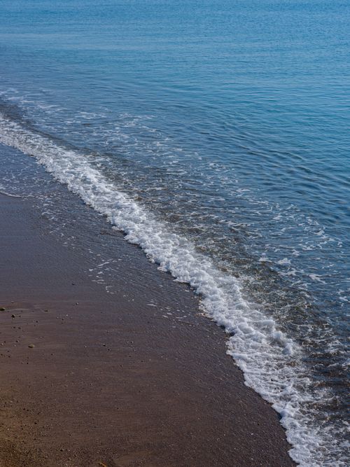 Free Peaceful beach scene with gentle waves lapping the sandy shore, perfect for relaxation concepts. Stock Photo