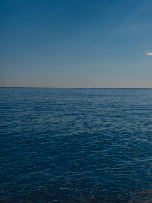 Free A tranquil ocean scene with a clear blue sky and calm waters. Stock Photo