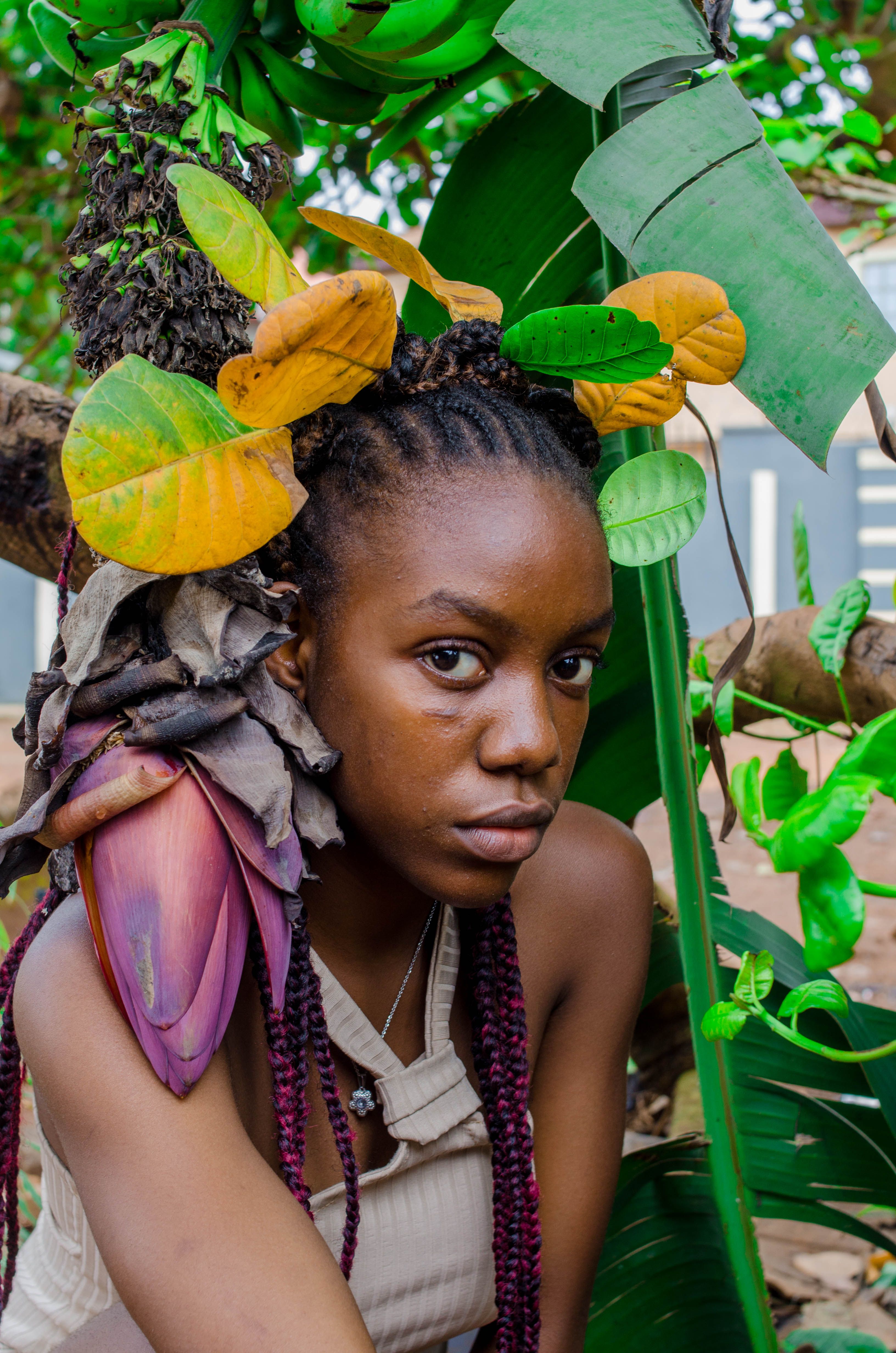 Vibrant portrait of a woman surrounded by lush green and yellow leaves, outdoors.