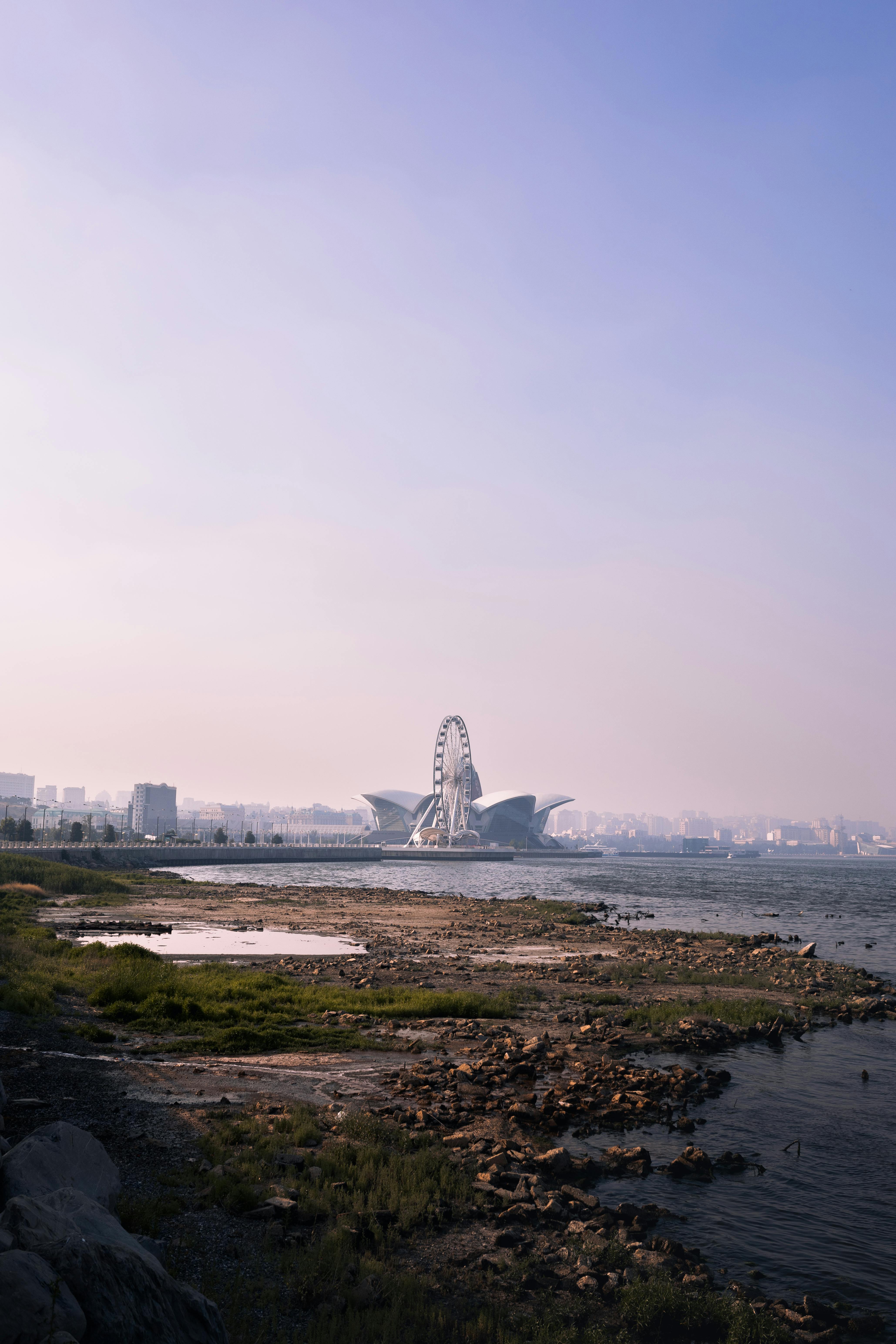 A scenic view of Baku's waterfront featuring a Ferris wheel and coastline with a hazy skyline.