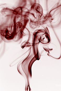 Abstract photo of red smoke creating fluid and intricate shapes against a plain background.