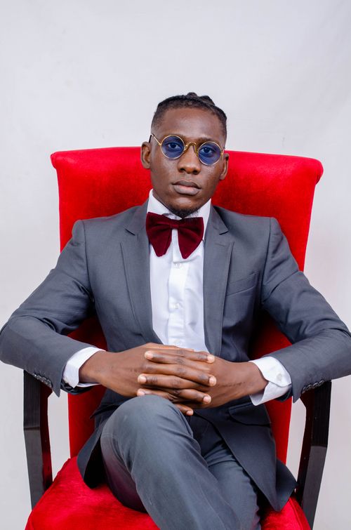 Free Confident young man in a gray suit and sunglasses sitting on a red armchair. Stock Photo