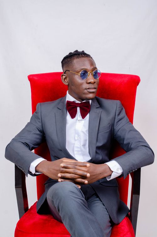 Free Stylish man in sunglasses sitting elegantly on a red chair in a studio. Stock Photo