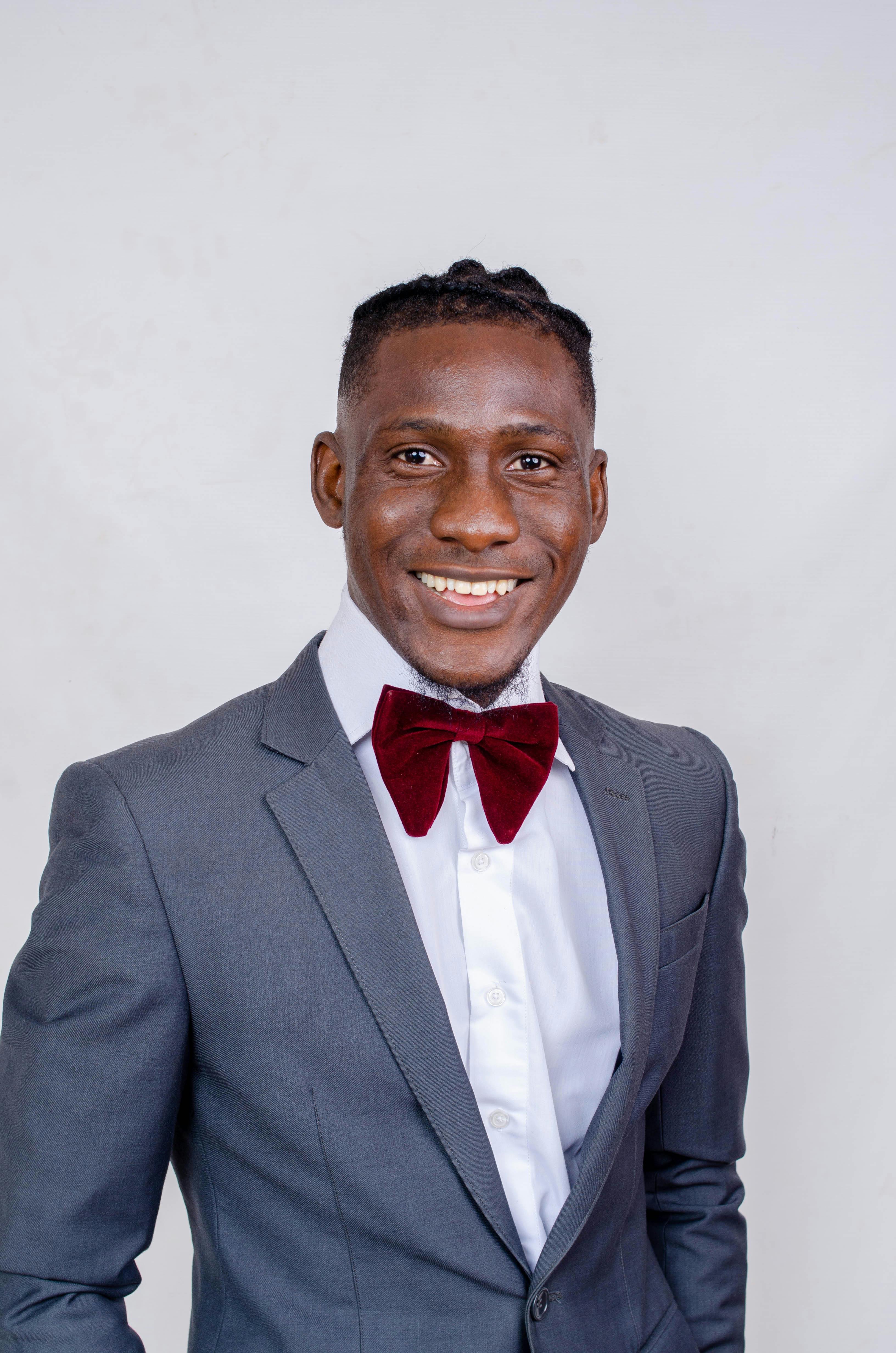 Portrait of an elegant man in a suit and bow tie, smiling confidently in a studio setting.