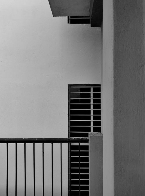 Free Elegant black and white photo of a minimalist architectural feature with railing and windows. Stock Photo