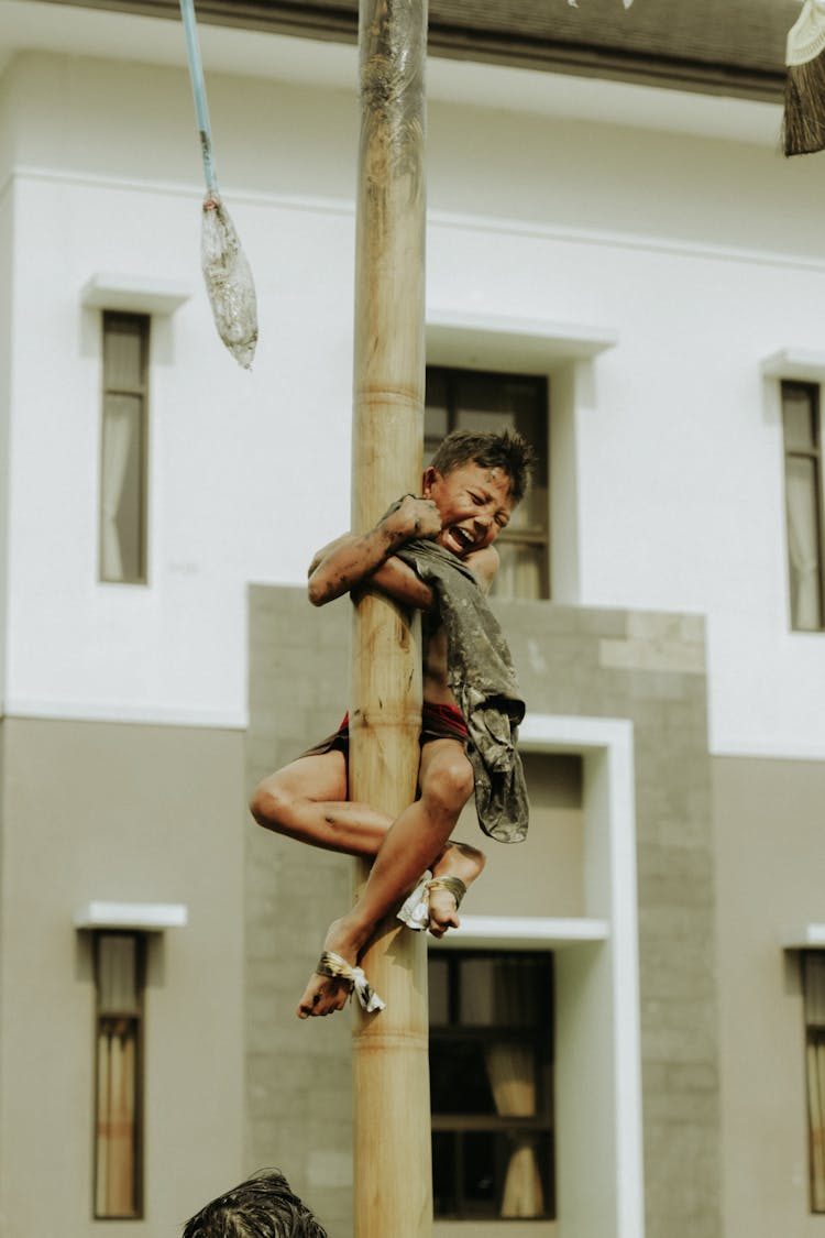 Boy Climbing Pole And Shouting