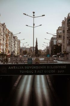 City street view in Antalya with footbridge and buildings under a clear sky.