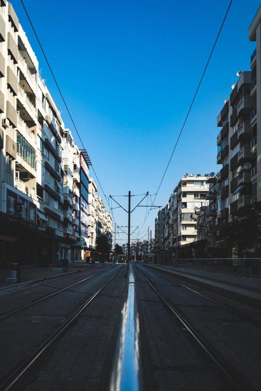 Street-level view down a wide city boulevard with tram tracks, lined with apartment blocks — Ayşegül Aytören on Pexels