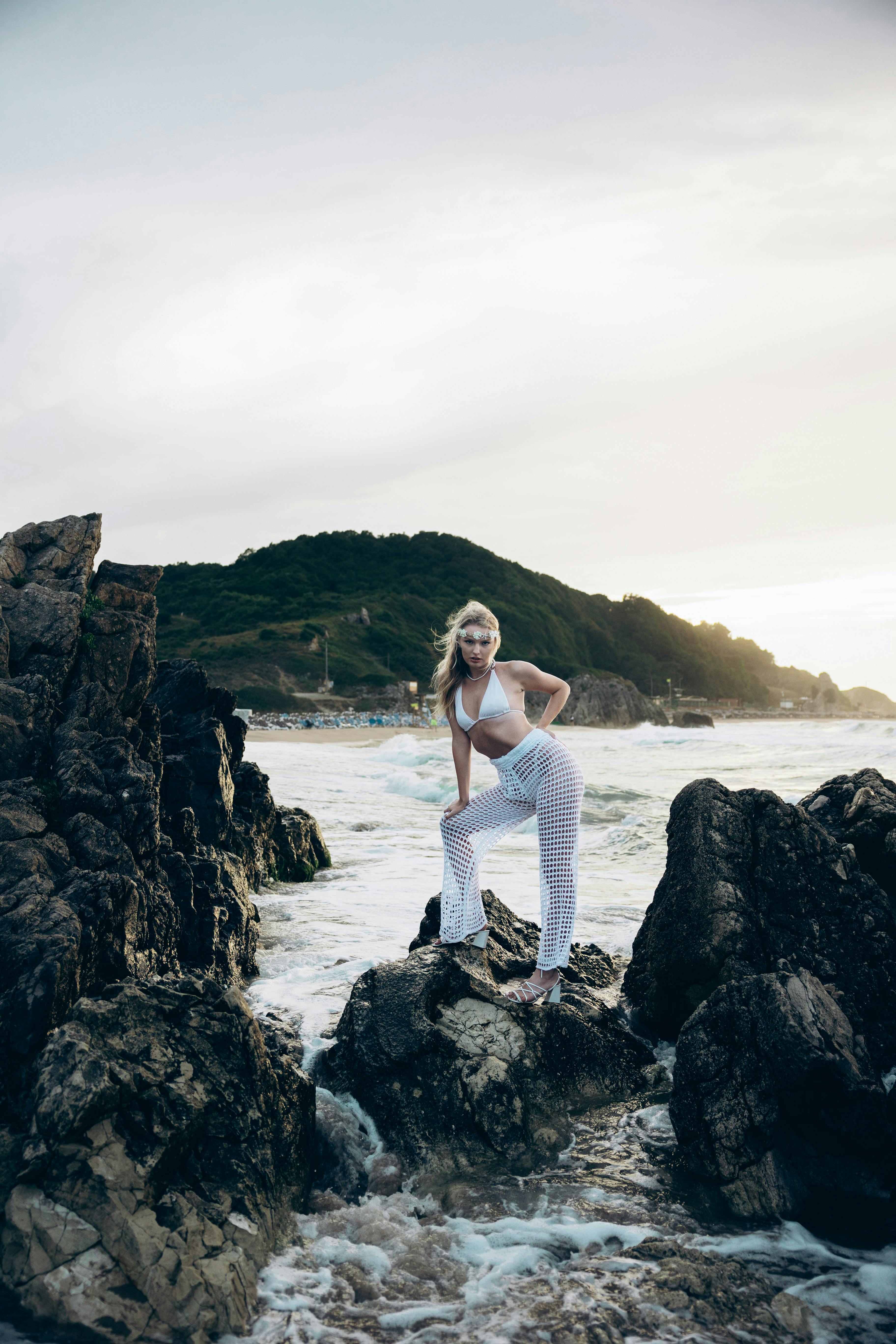 a woman in white pants standing on rocks