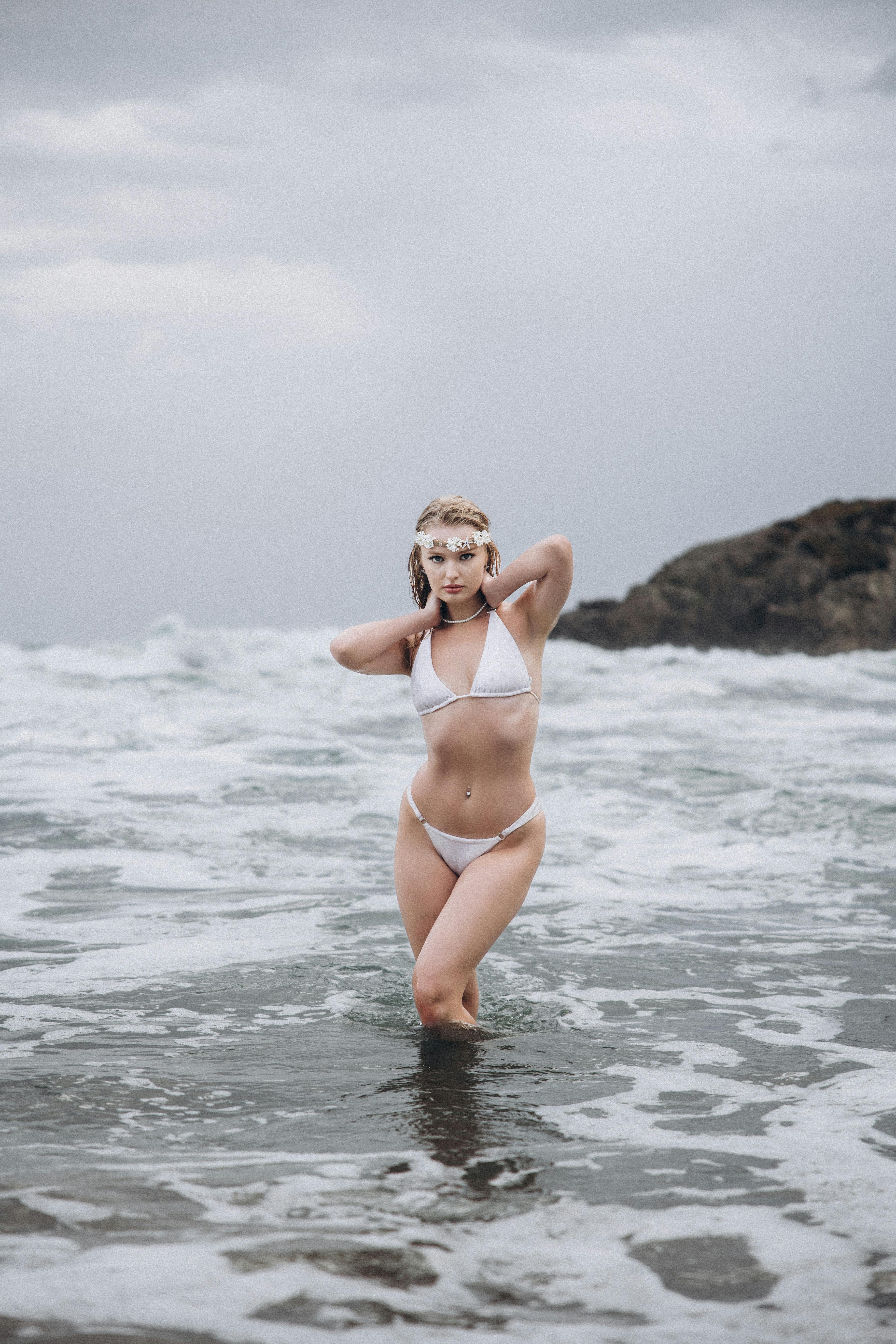 a woman in a white bikini standing in the ocean