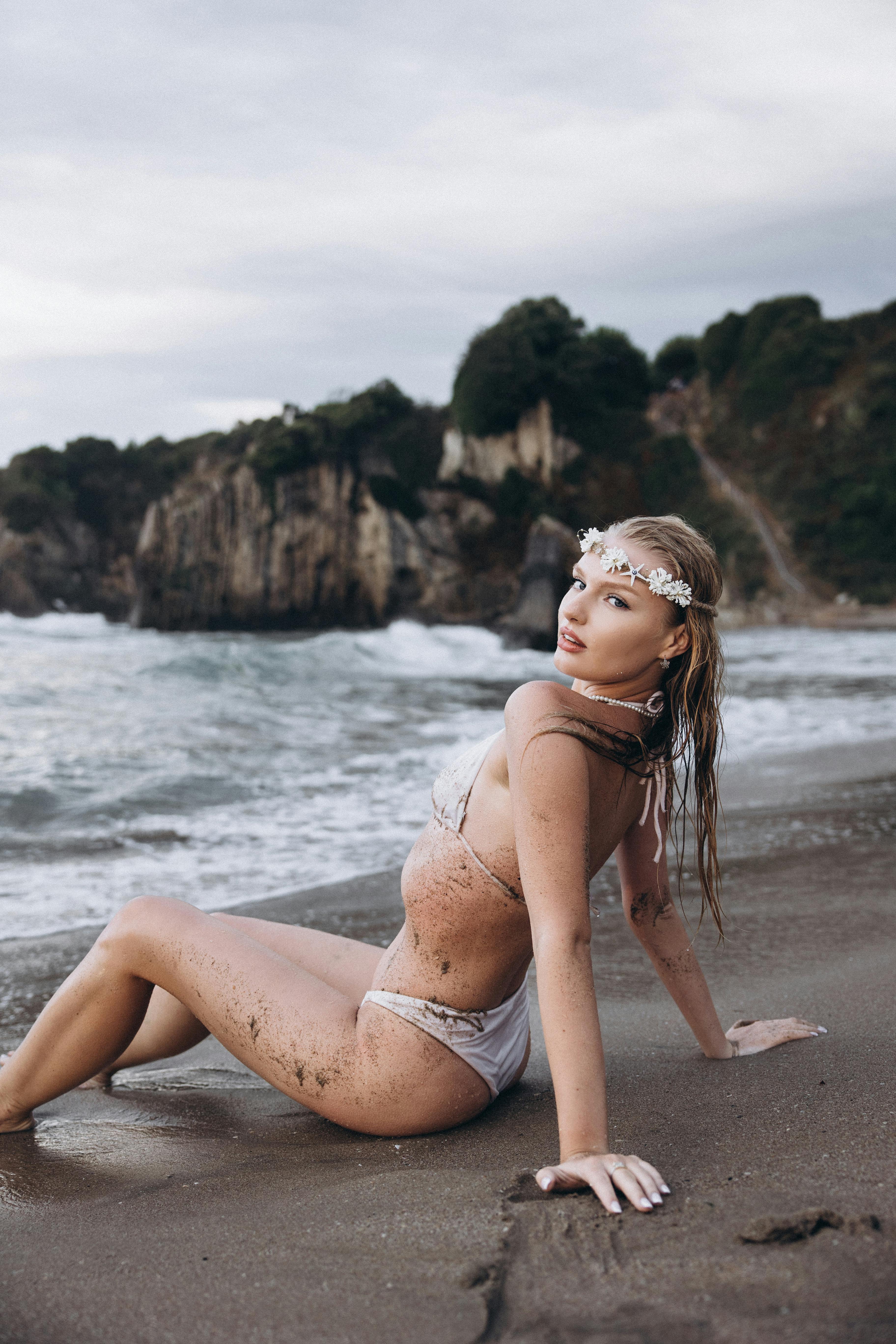 a woman in a white bikini sitting on the beach